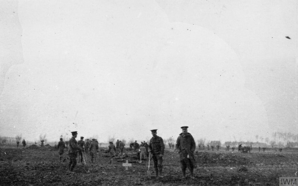 Photographie en noir et blanc : quelques soldats debout dans un champ plat, sur le front de l’Ouest